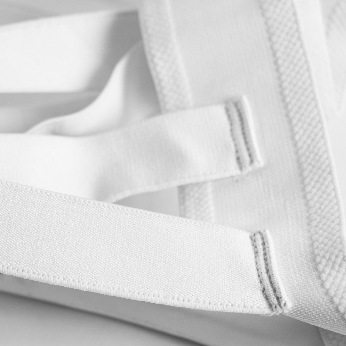 Close-up of white Adidas WKF women's protective groin guard with elastic straps for martial arts and combat sports