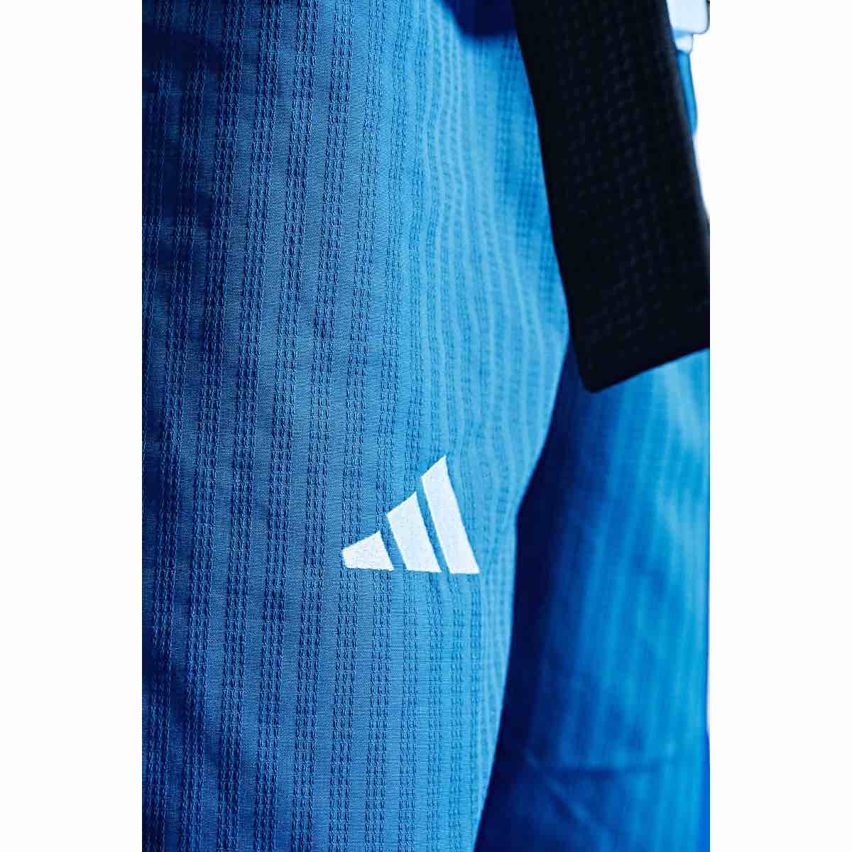 Close-up of light blue adidas Dobok Taekwondo pants with white logo and black belt for women Poomsae competitions