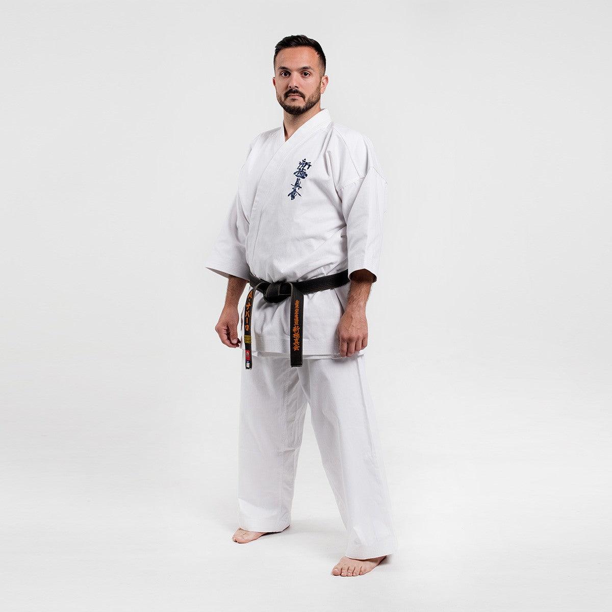 Man wearing traditional white Shinkyokushin Yantsu Karate Gi with black belt standing on white background