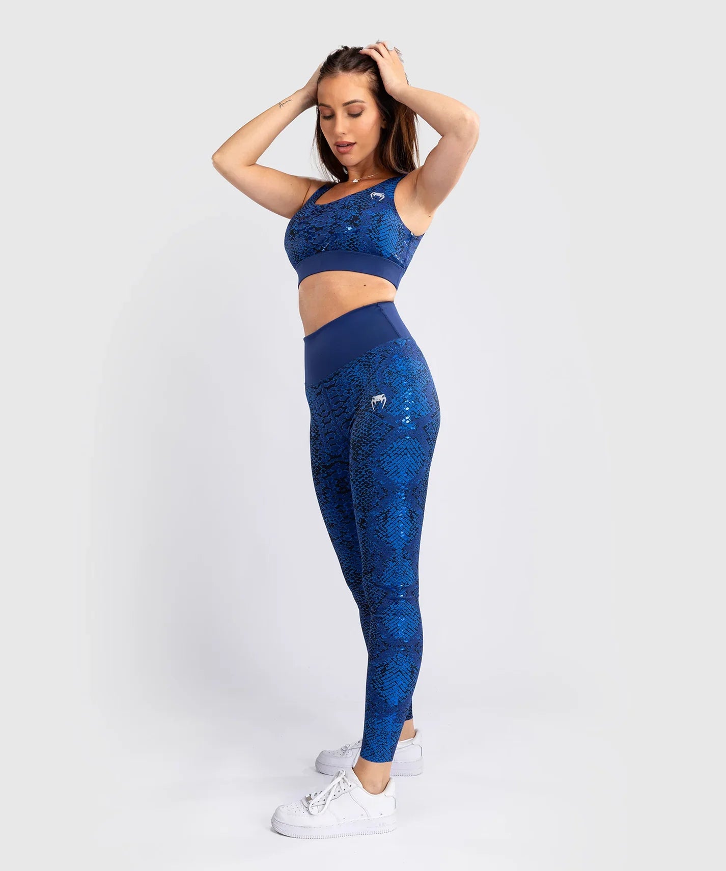 Woman wearing ultramarine Venum Amazonia long leggings with snake skin pattern and matching sports bra for fitness and combat sports