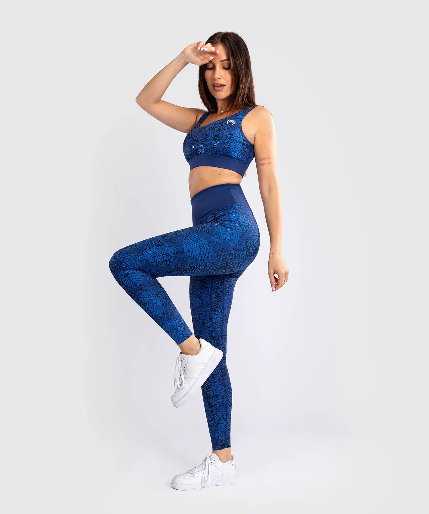 Woman wearing ultramarine Venum Amazonia long leggings with snake skin pattern and matching sports bra in fitness pose