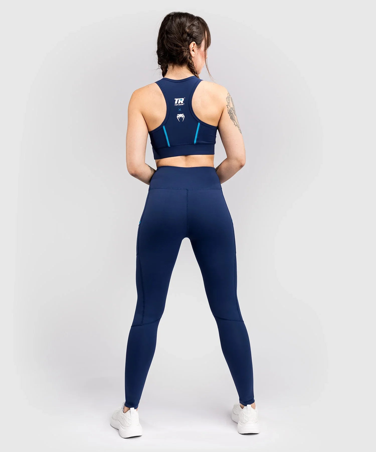 Woman wearing navy blue compressive long leggings from Venum x Top Rank athletic collection, shown from the back
