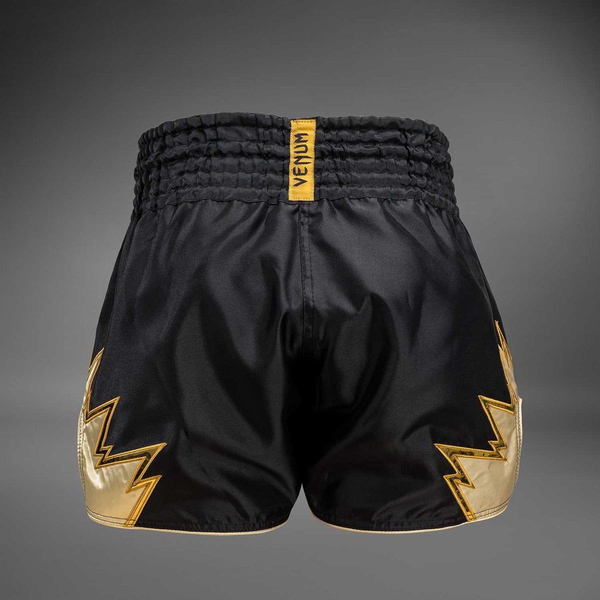Short de Muay Thaï Venum Inferno noir et or, tissu léger et fentes latérales pour mobilité optimale.