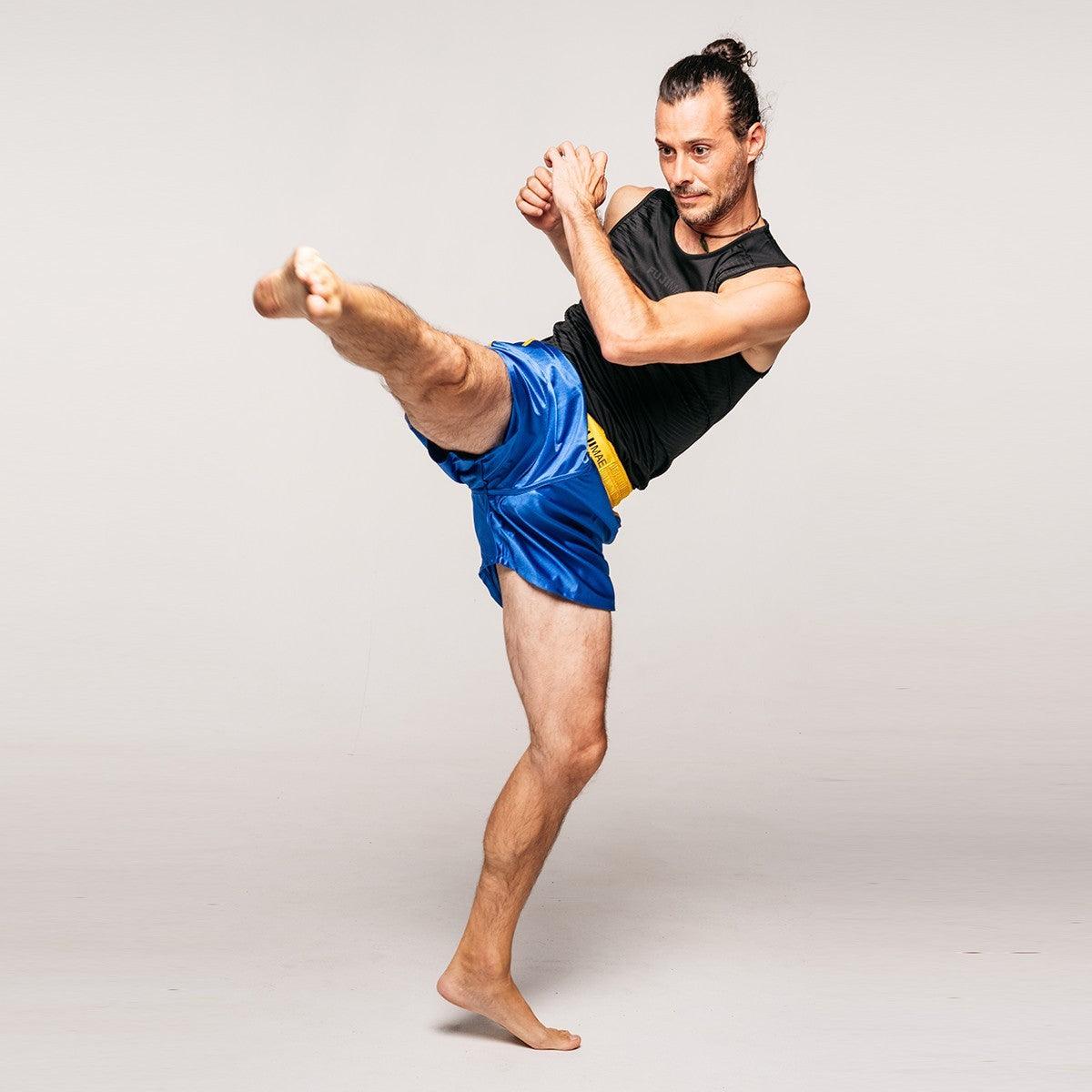 Man performing high kick wearing blue Shorts de Sanda Training with elastic waistband and sleeveless black top