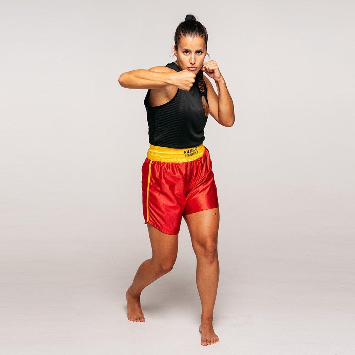 Woman wearing red and yellow Shorts de Sanda Training in a fighting stance for martial arts training