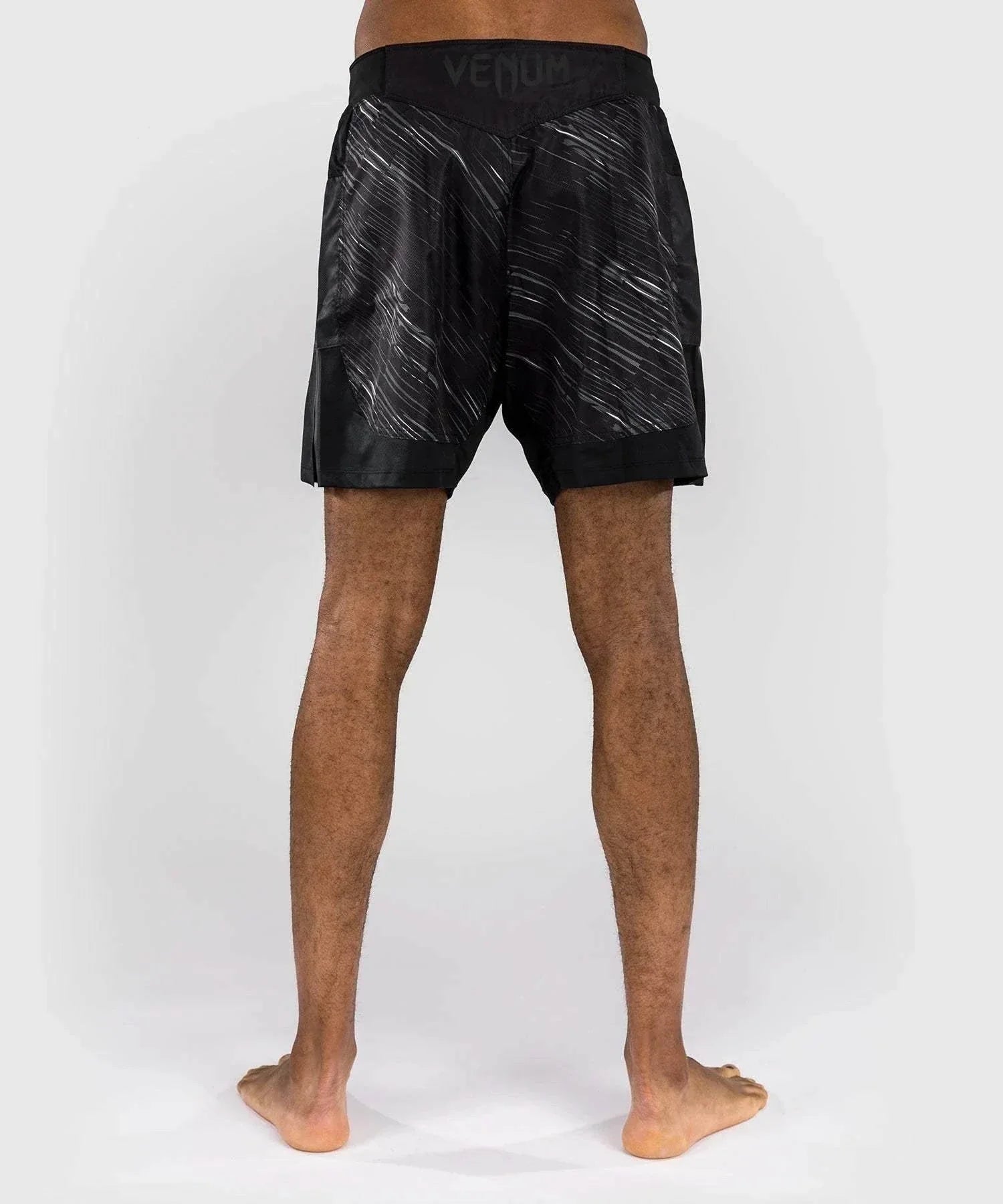 Back view of a person wearing black and gray Fightshort Venum Rapid combat shorts with a lightweight ripstop fabric and deep side slits for maximum movement.