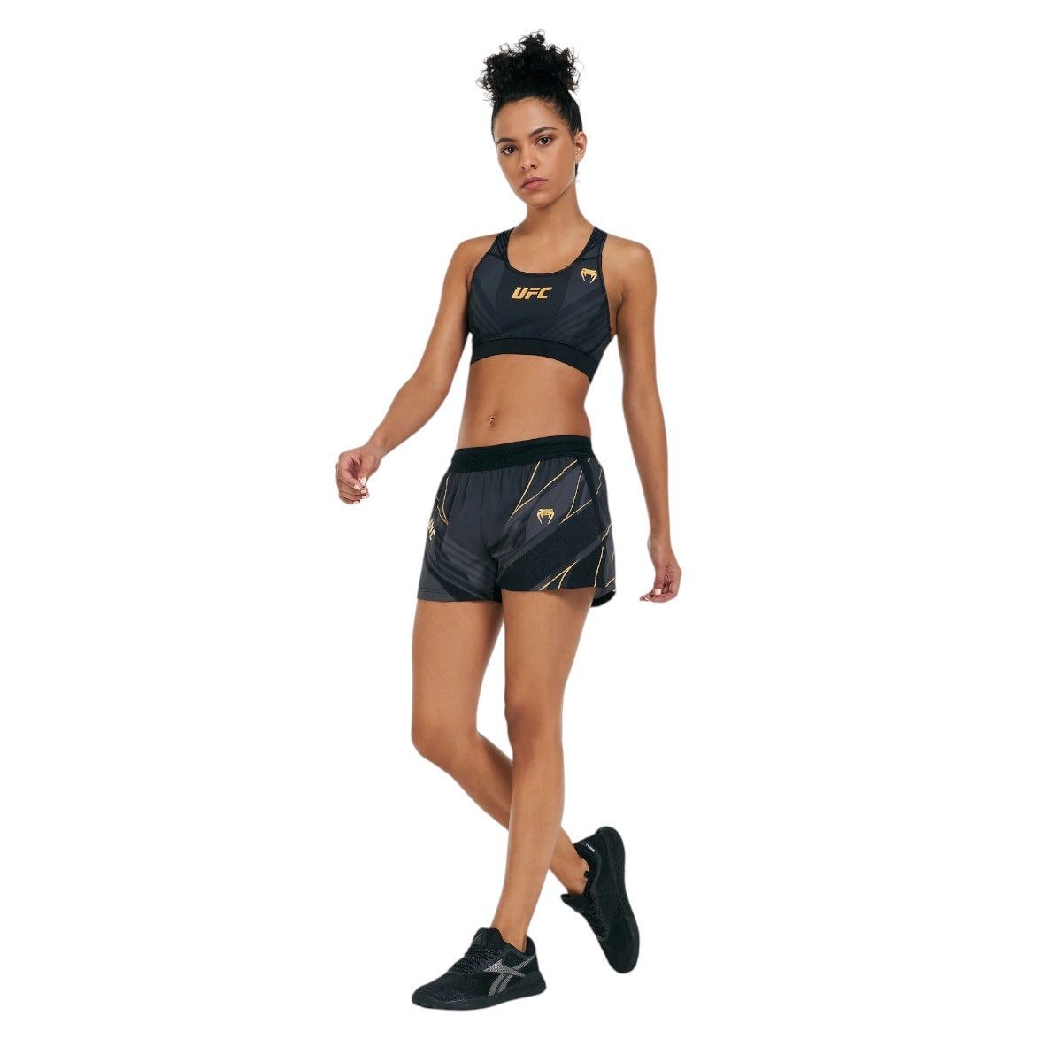 female athlete wearing black and gold UFC Venum Replica Champion lightweight breathable sports shorts and matching sports bra