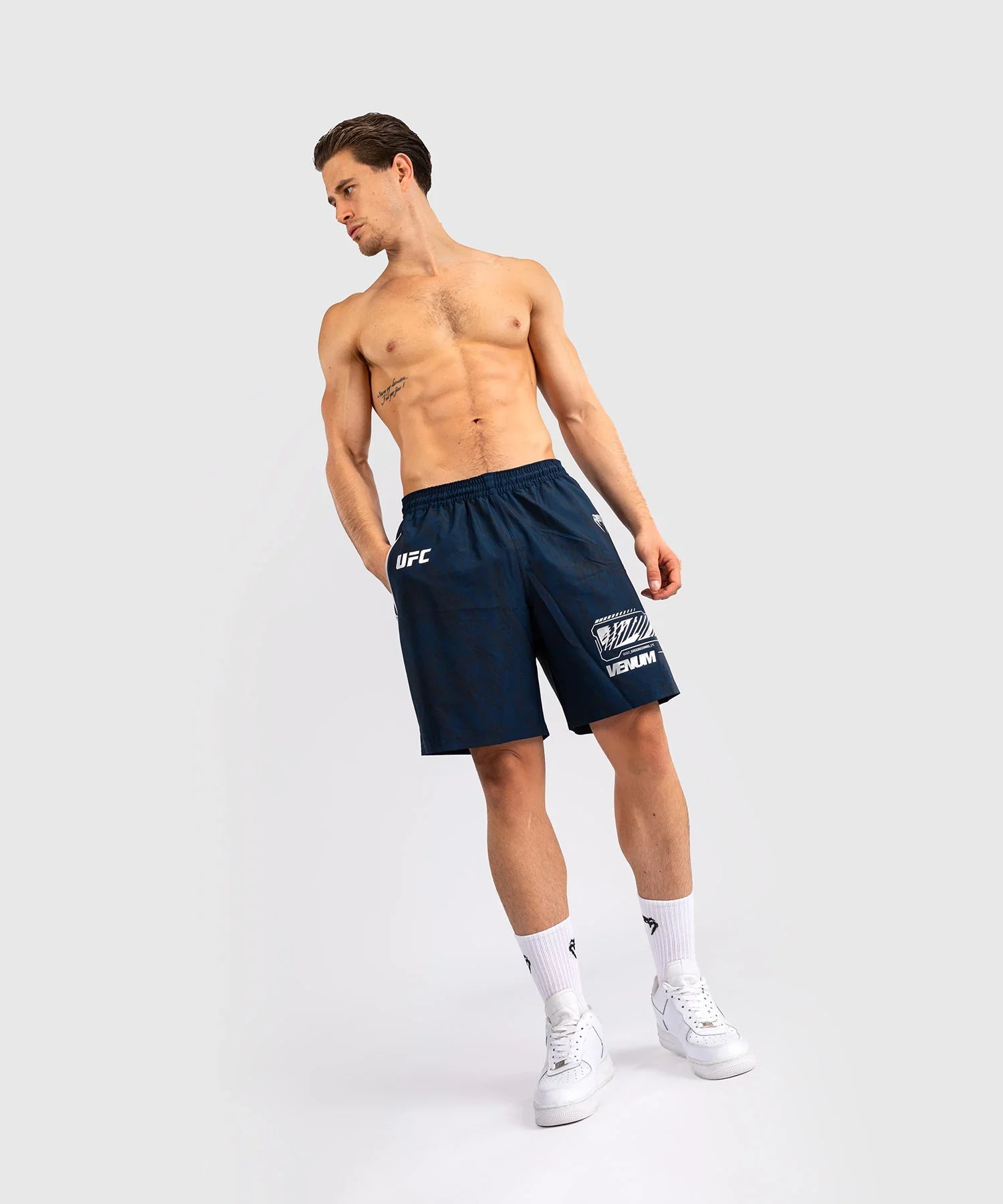 Athlete wearing navy blue UFC Fusion par Venum performance shorts with elastic waistband and logos, designed for training and flexibility