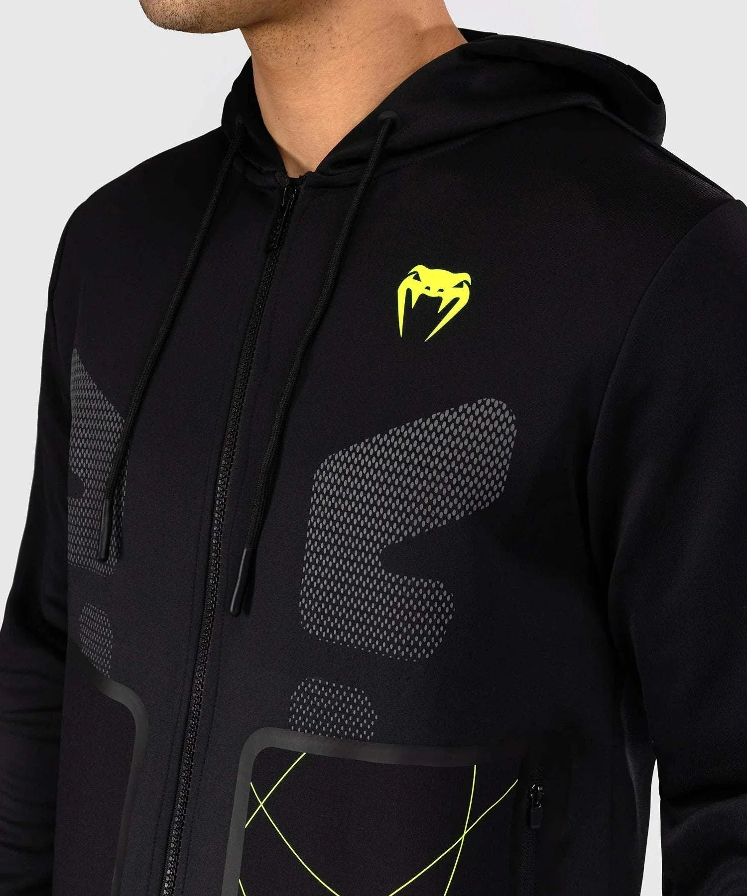 Black zip-up Venum Training Camp 4.0 hoodie with neon green logo and accents, made of breathable Dry Tech polyester, featuring adjustable hood and zippered pockets.
