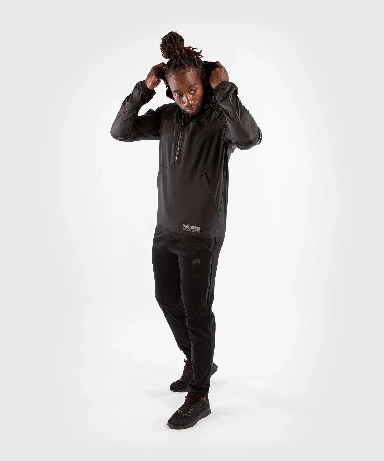man wearing black Venum Laser XT hoodie sweatshirt and matching black jogging pants adjusting hood