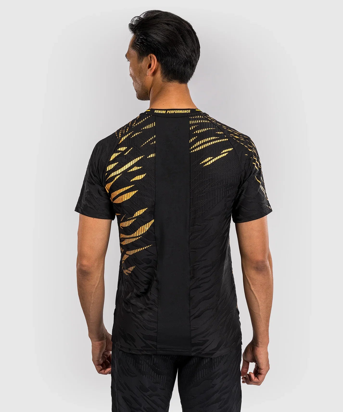 Back view of a man wearing black and gold UFC Fusion par Venum Dry-Tech short sleeve performance T-shirt