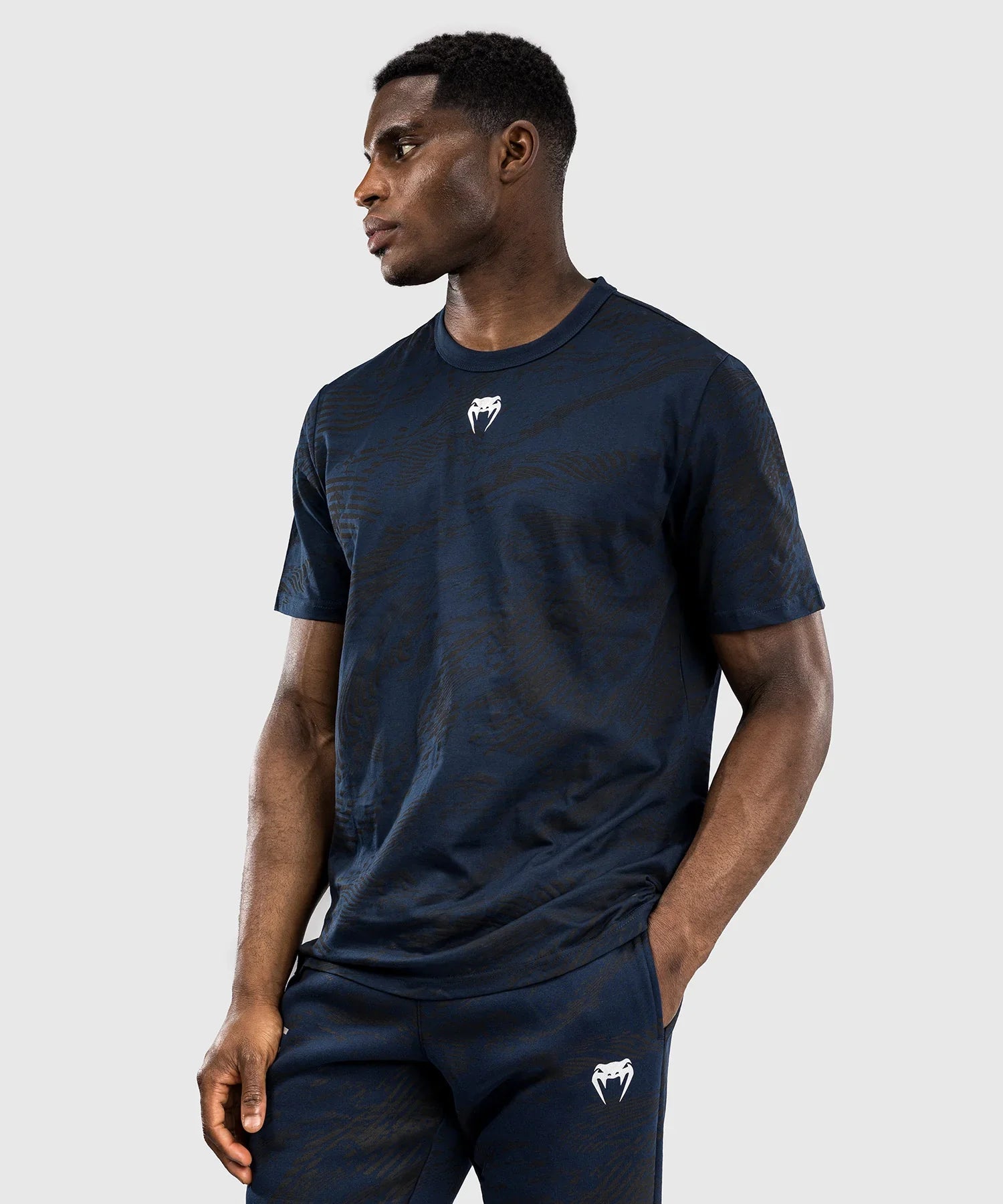 Man wearing navy blue UFC Fusion par Venum short-sleeve cotton t-shirt with white logo on chest and matching pants against gray background