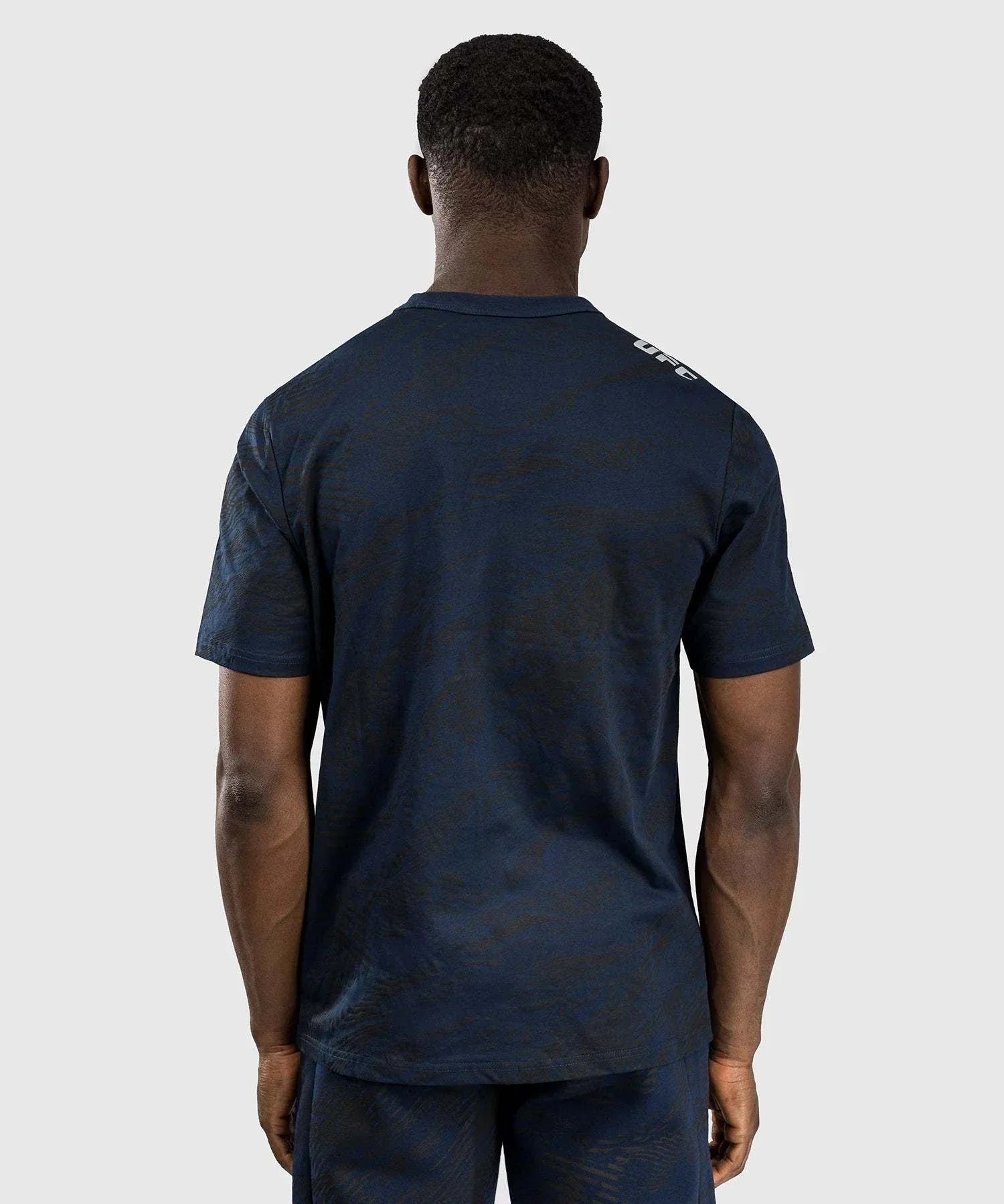 Back view of a man wearing a navy blue UFC Fusion par Venum authentic fight week T-shirt with short sleeves and a regular fit.
