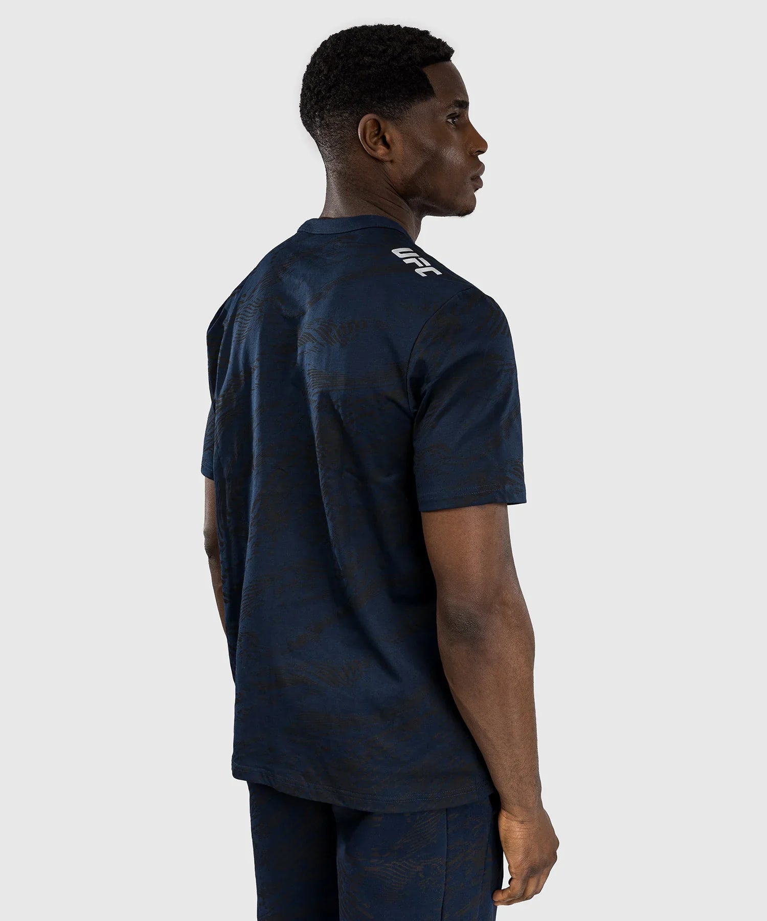 Man wearing dark blue UFC Fusion par Venum T-shirt with short sleeves and round neck, back view