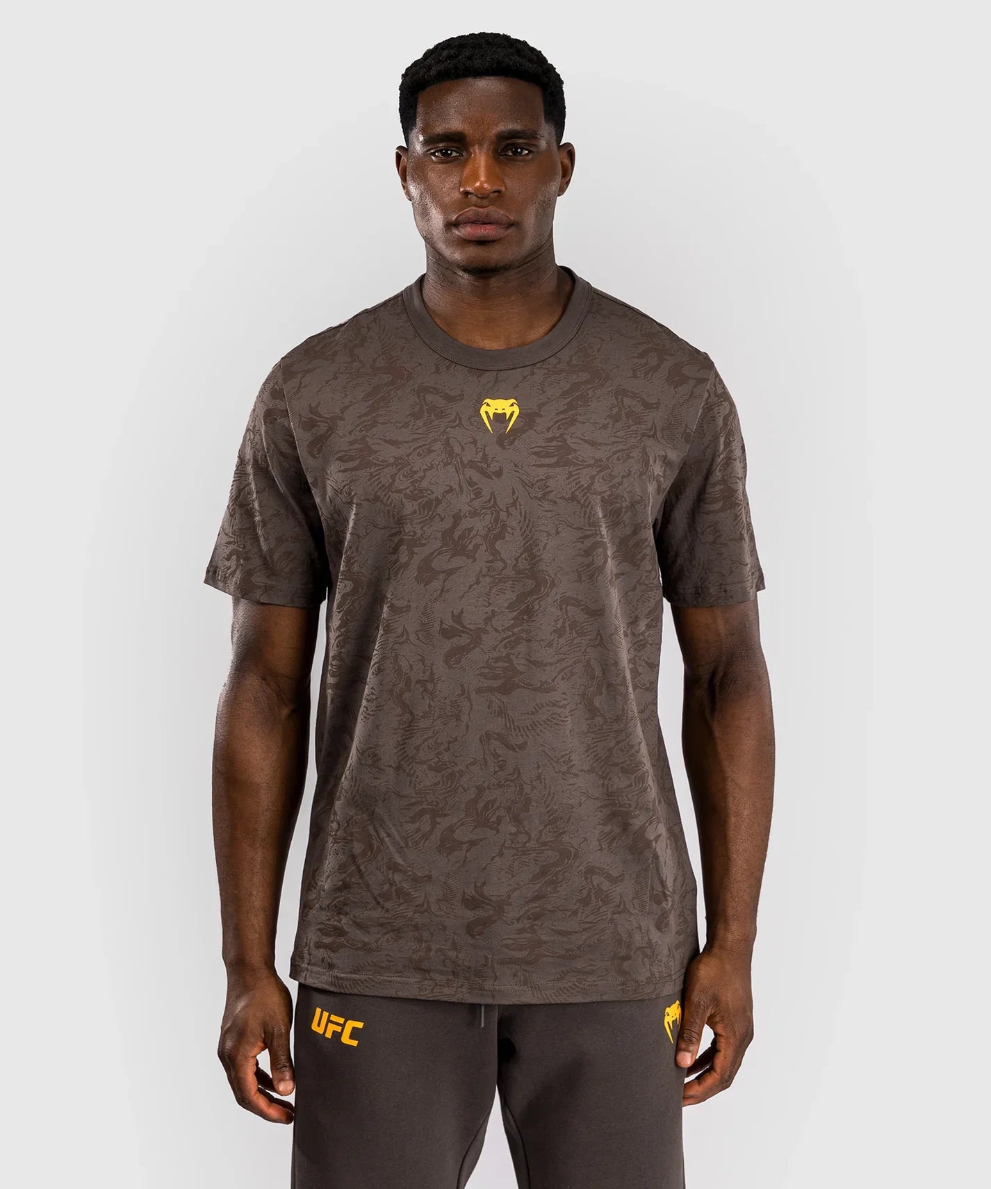 Male model wearing brown UFC Fusion par Venum short sleeve cotton t-shirt with yellow logo and subtle nature-inspired pattern