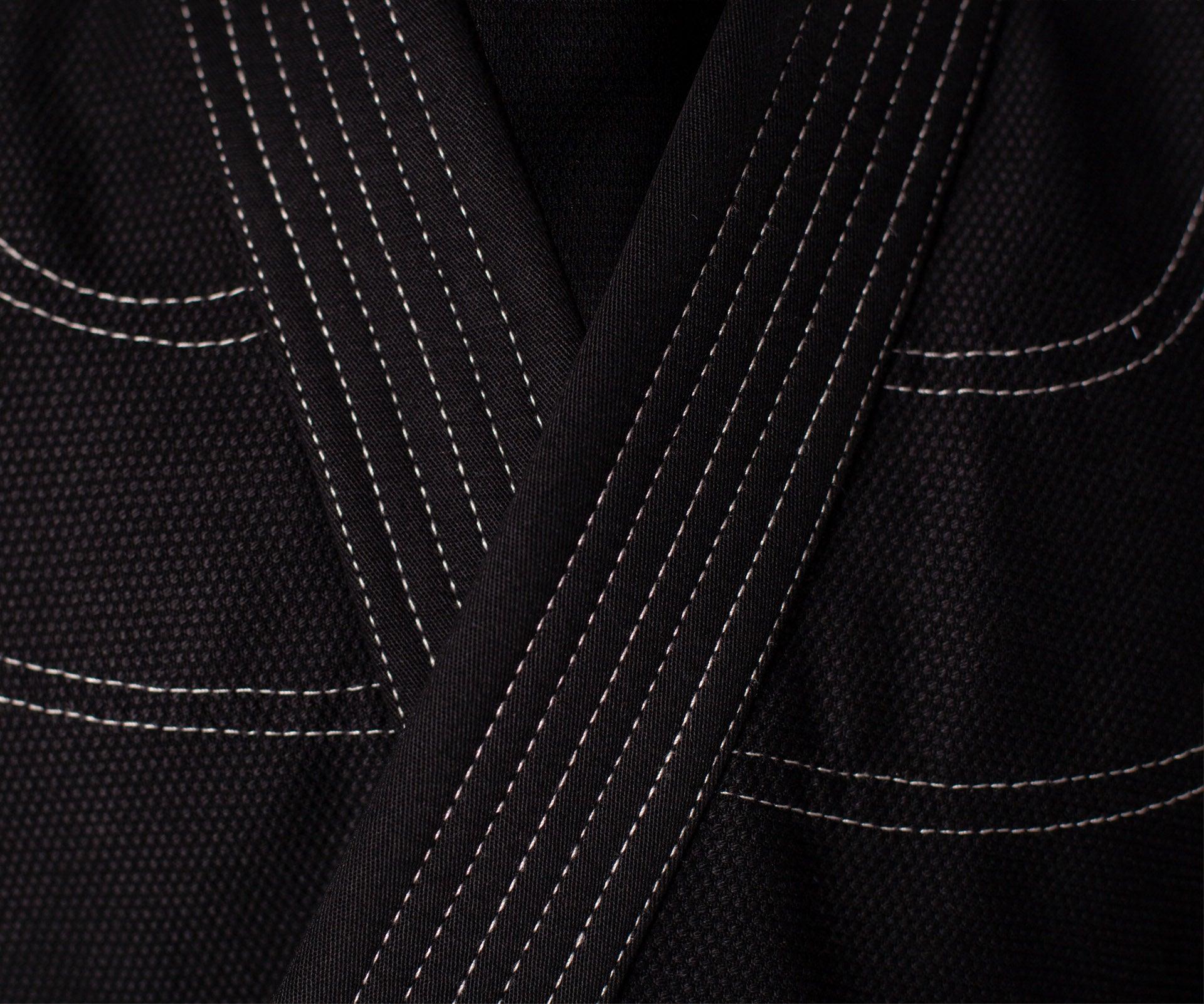 Close-up of black DANRHO Kimono Brazilian Jiu Jitsu jacket with pearl weave fabric and contrast stitching