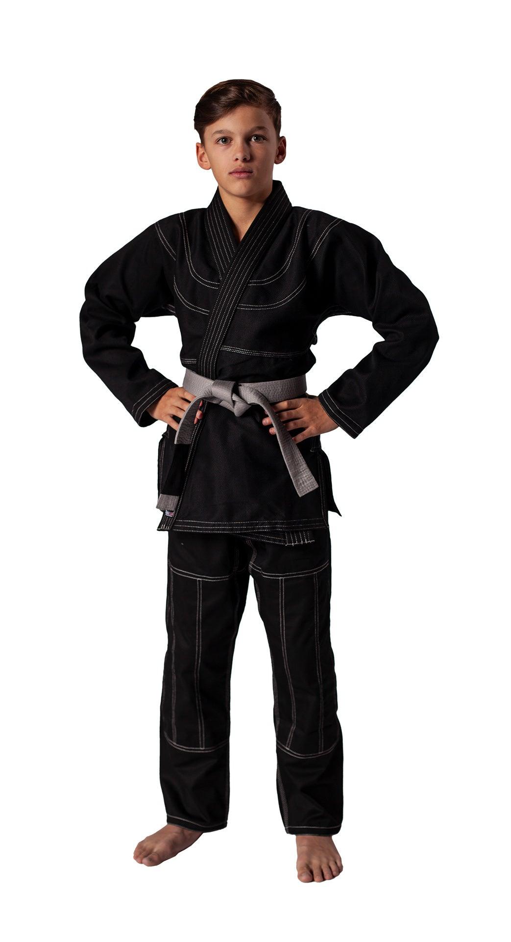 Child wearing black Kimono Brazilian Jiu Jitsu DANRHO with gray belt, standing confidently against white background