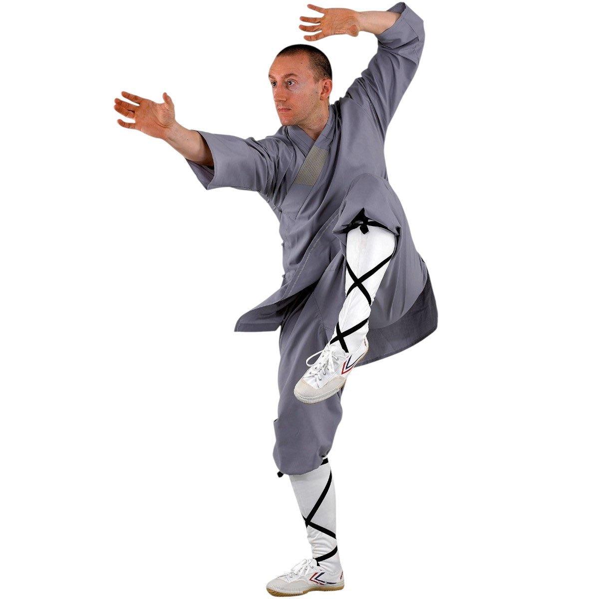 Man practicing Kung Fu wearing traditional grey Tenue de Moine Shaolin monk outfit with white socks and sneakers