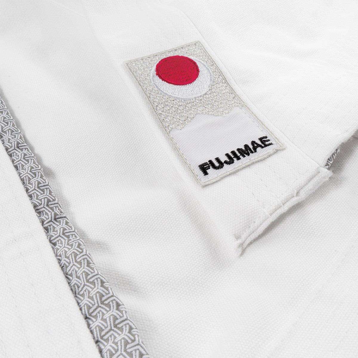 Close-up of white FUJIMAE Legacy II karate kimono jacket with Japanese-style patterned trim and embroidered logo patch