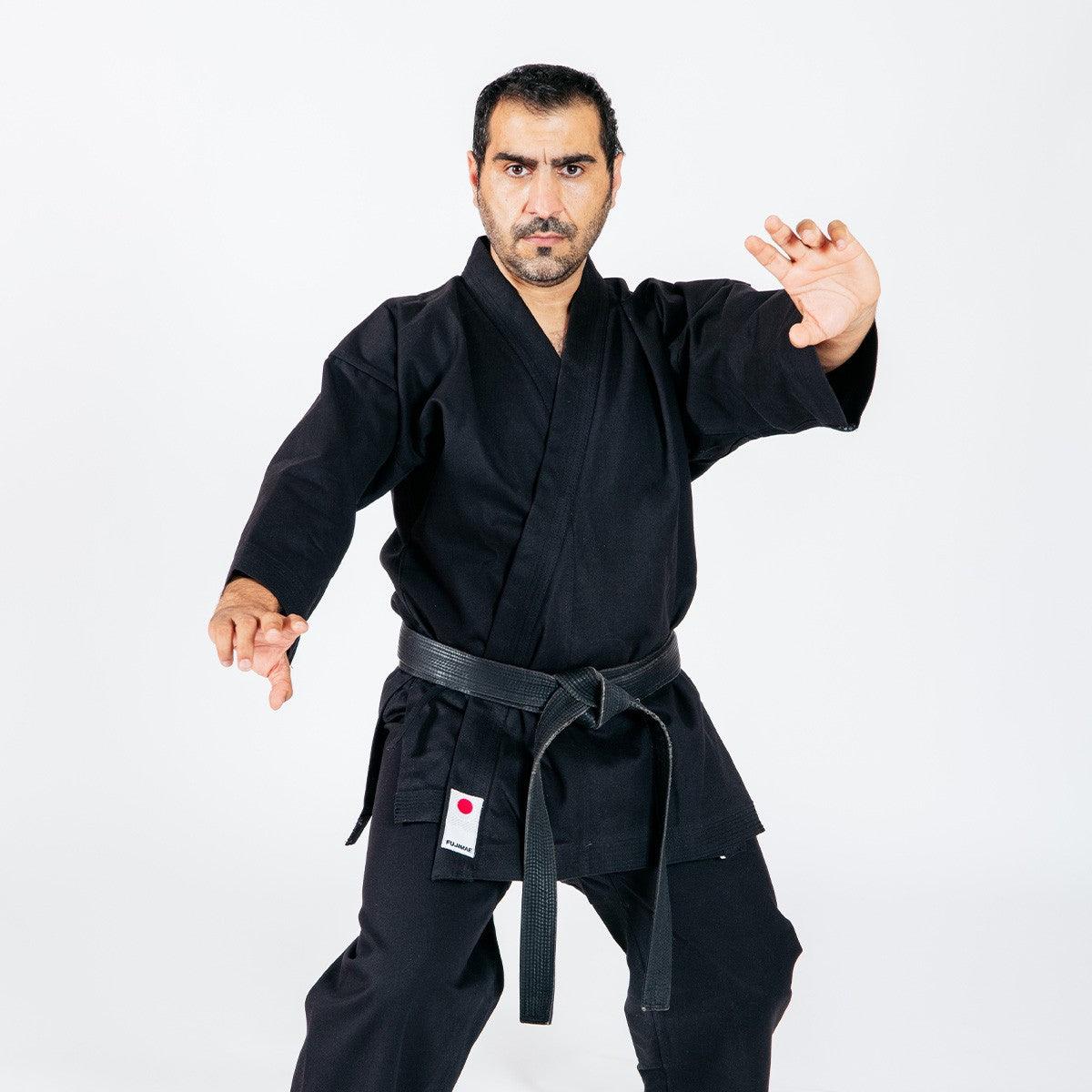 Man wearing black Veste de Karaté-gi Legacy II karate jacket and black belt in martial arts stance