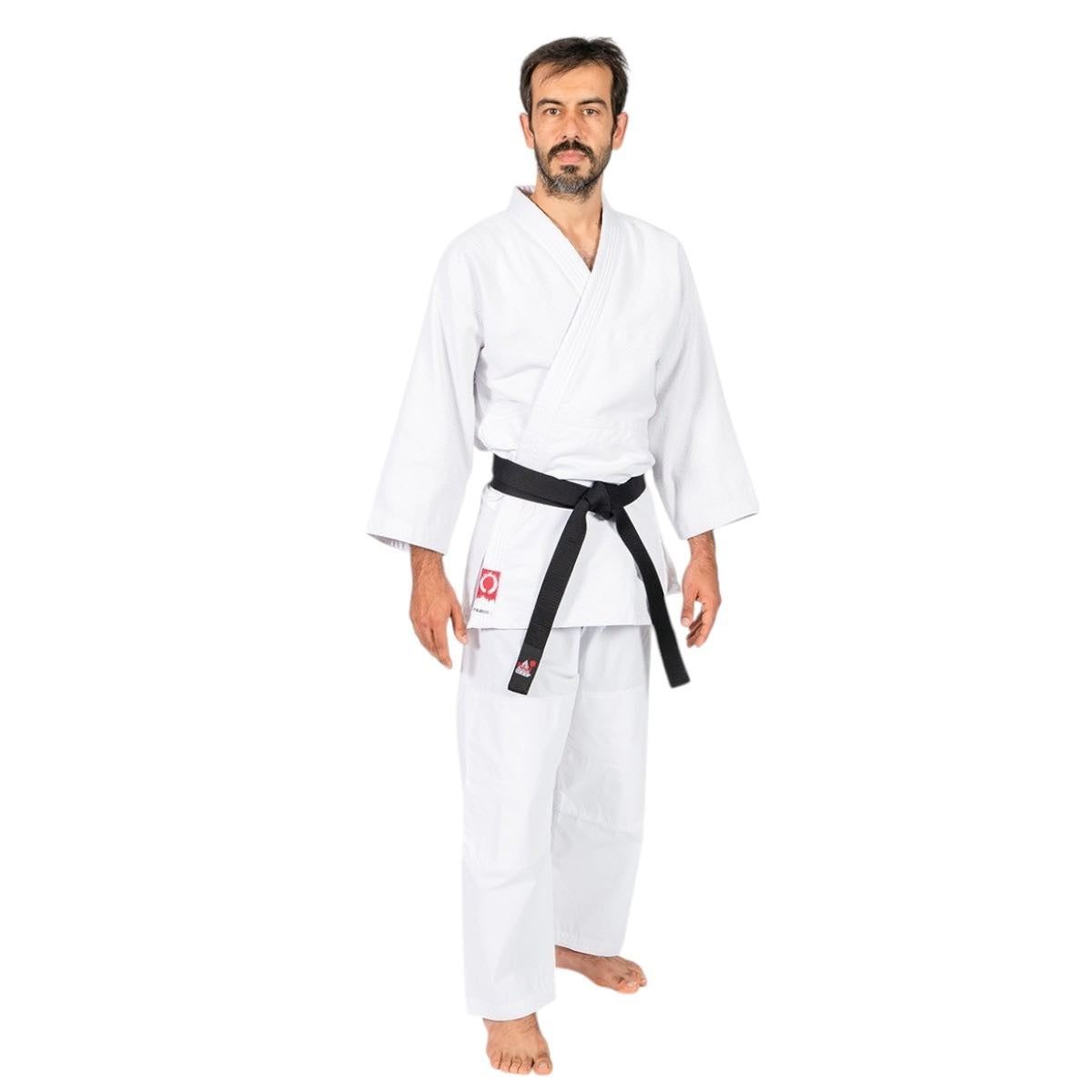 Man wearing white Keikogi Aïkido FUJIMAE gi with black belt, standing barefoot on white background