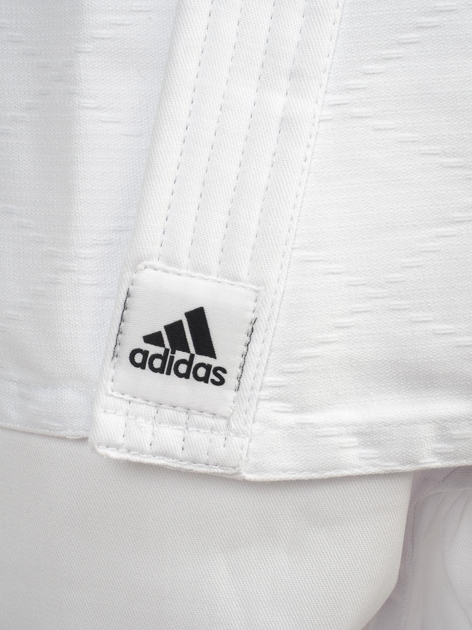 Close-up of white Adidas judo kimono with black logo patch and reinforced stitching designed for beginner judokas