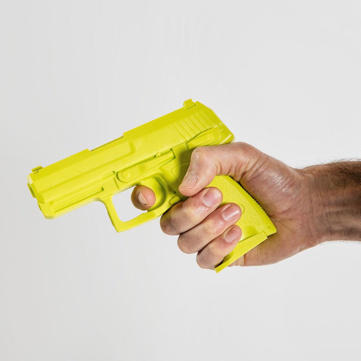 Hand holding a yellow FUJIMAE SD-H93C training pistol made of durable thermoplastic rubber for realistic self-defense training