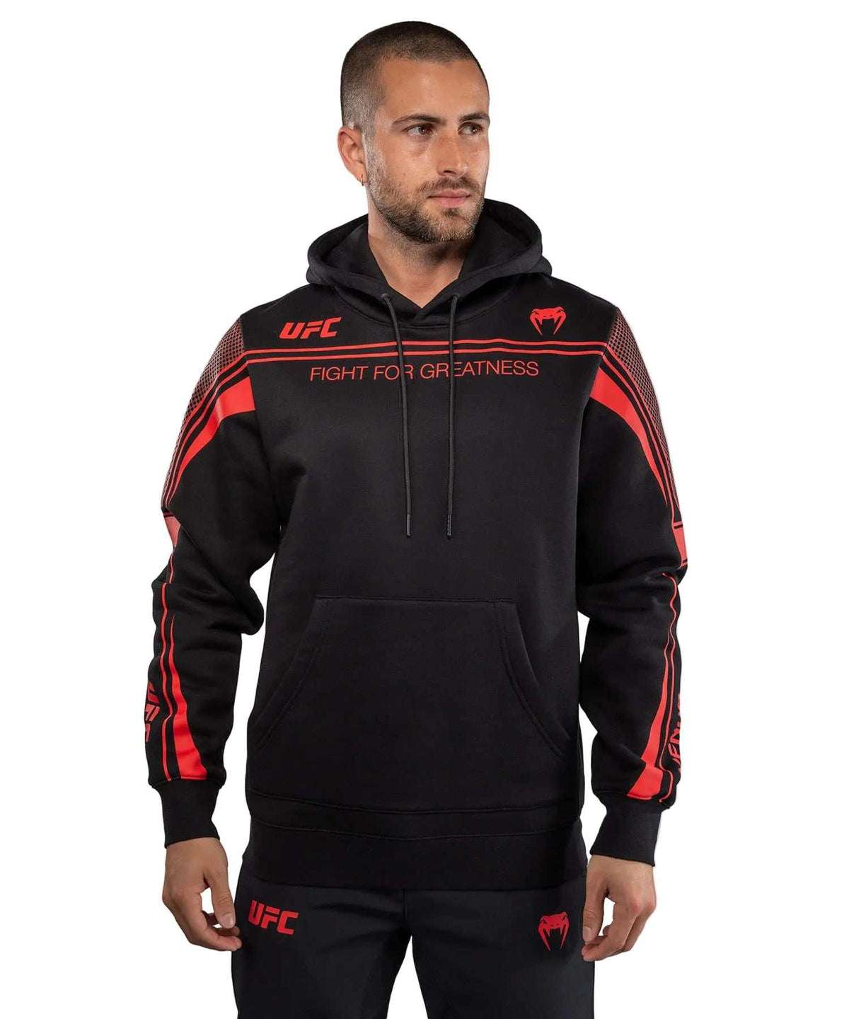 Sweat à Capuche noir à capuche et poche kangourou, avec bandes rouges, logos UFC et inscription « Fight for Greatness ».