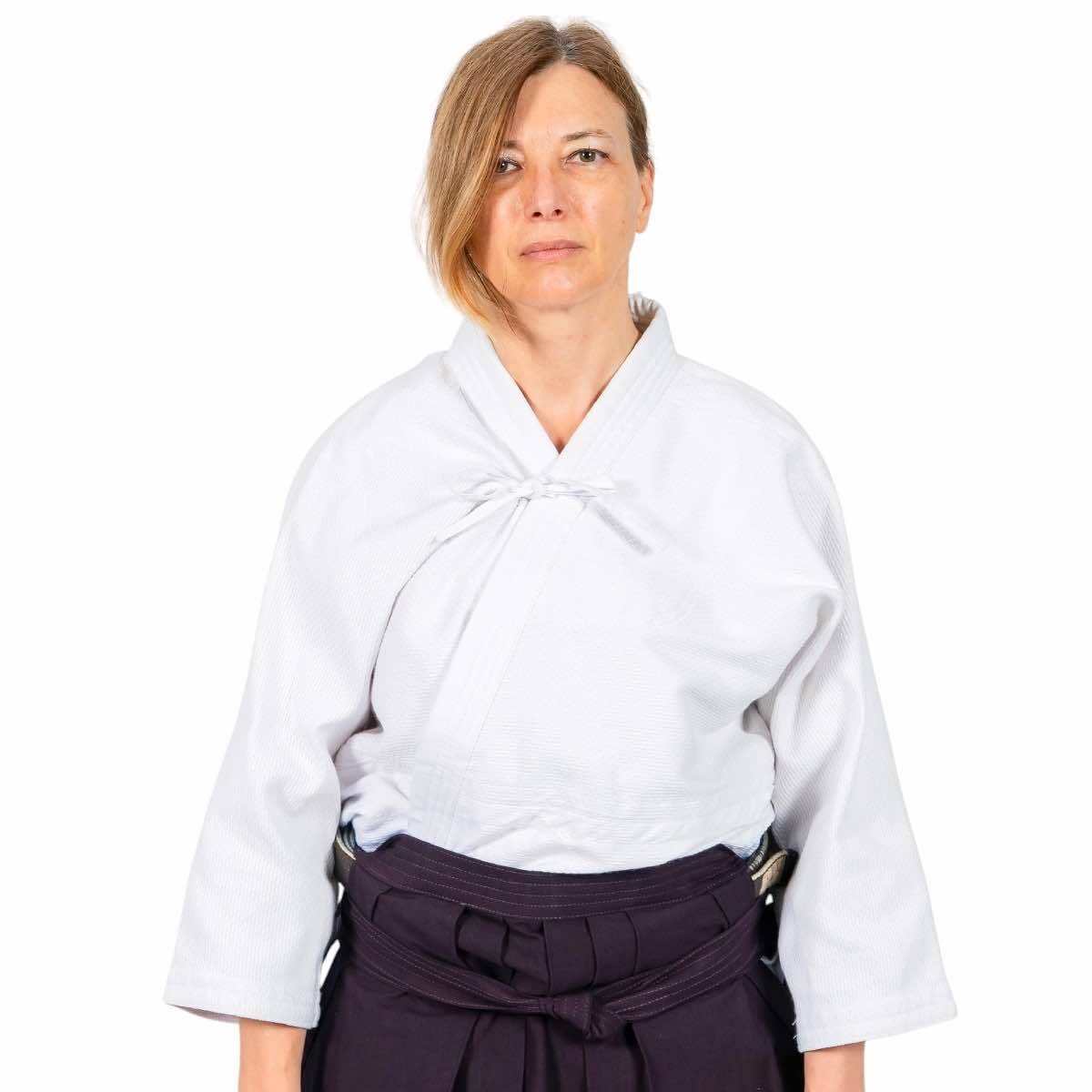 Woman wearing white Fujimae Keikogi Aïkido gi training jacket with tailored female cut and black belt