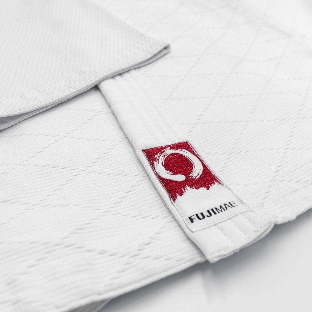 Close-up of white Keikogi Aïkido FUJIMAE gi fabric with brand logo patch