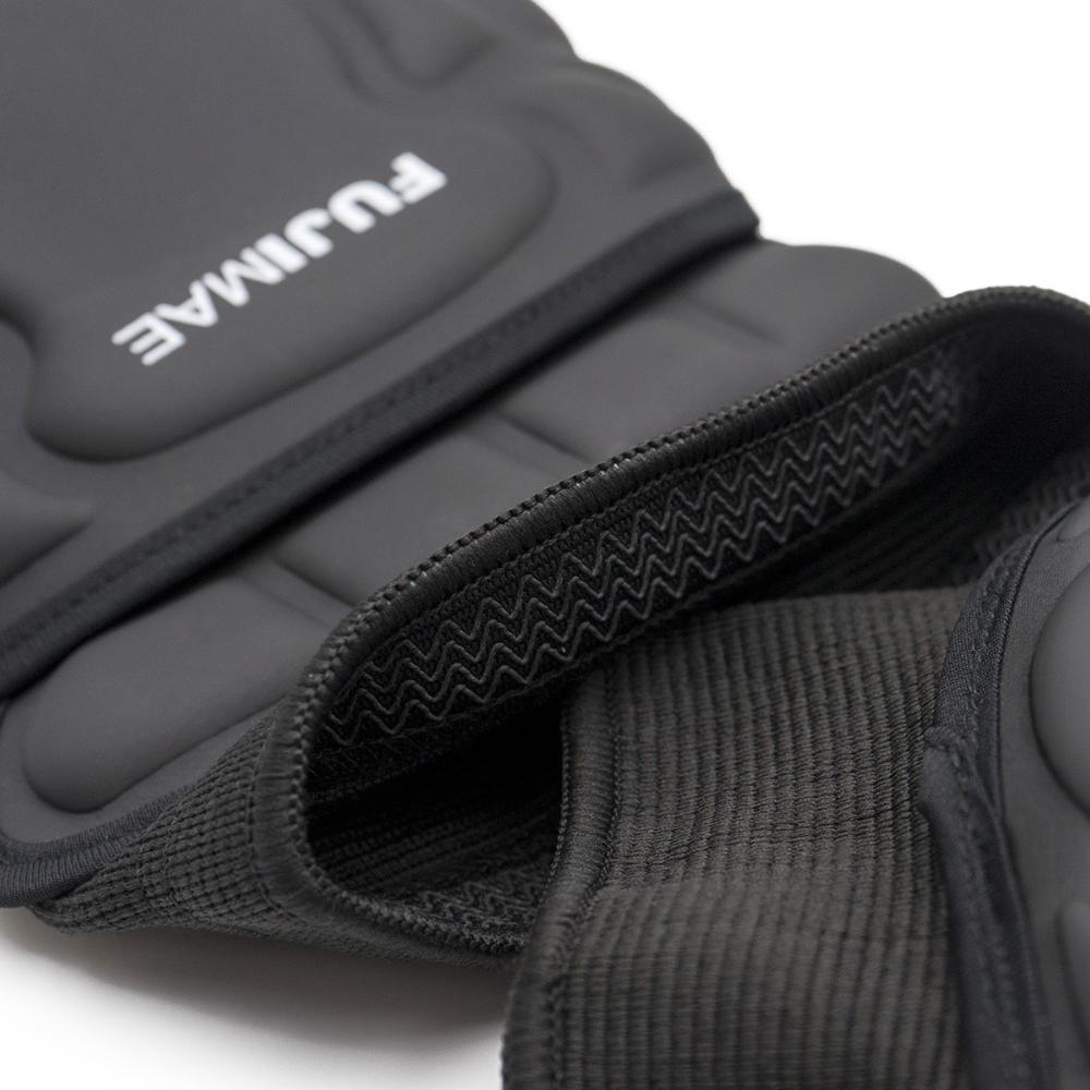 Close-up of black FUJIMAE ProSeries knee pads with ergonomic design and anti-slip strap for martial arts and self-defense.