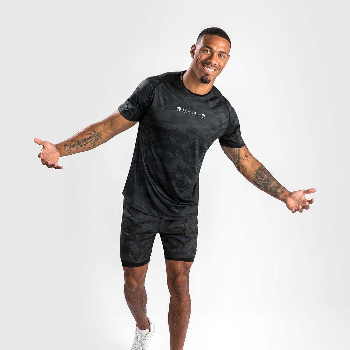 Man wearing black and gray Venum Electron 3.0 Dry Tech short sleeve T-shirt and matching shorts with white sneakers
