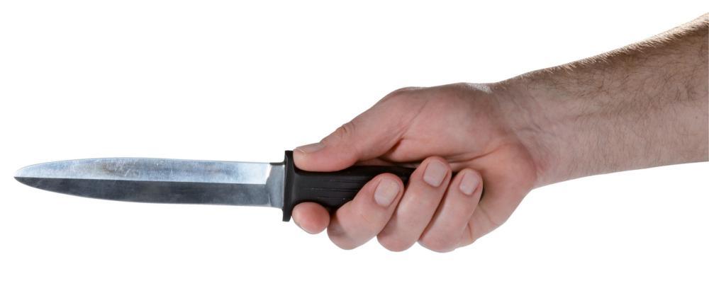 Hand holding a black and metal aluminum training boot knife with rounded tip for martial arts and self-defense practice.