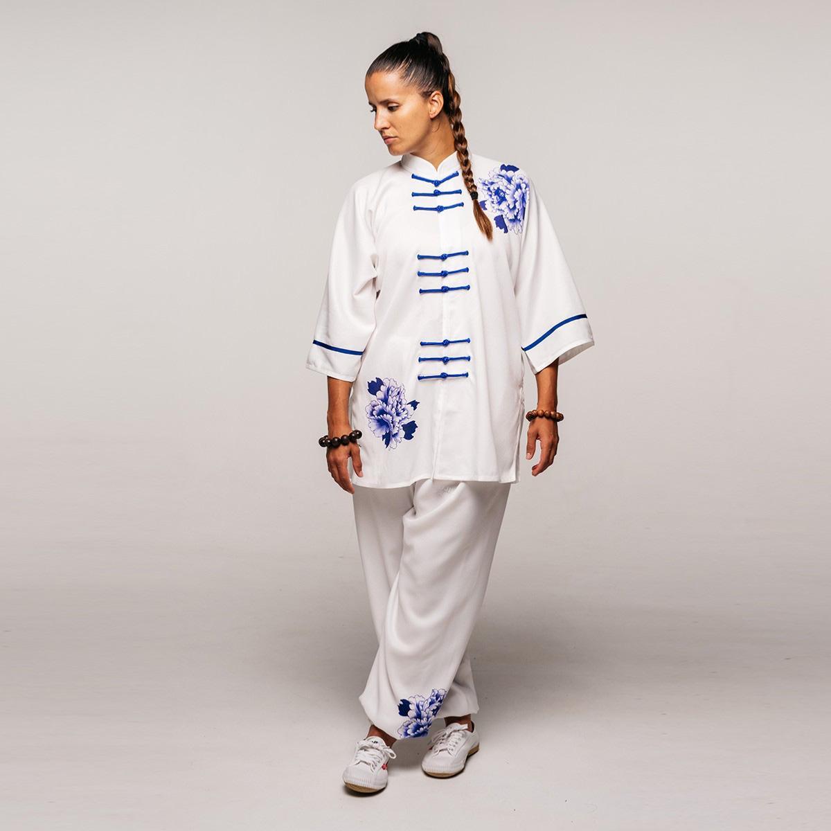 Woman wearing white and blue Tenue Tai Chi Chuan FUJIMAE Qïng Porcelain uniform with traditional Chinese floral motifs and loose fit for Tai Chi practice