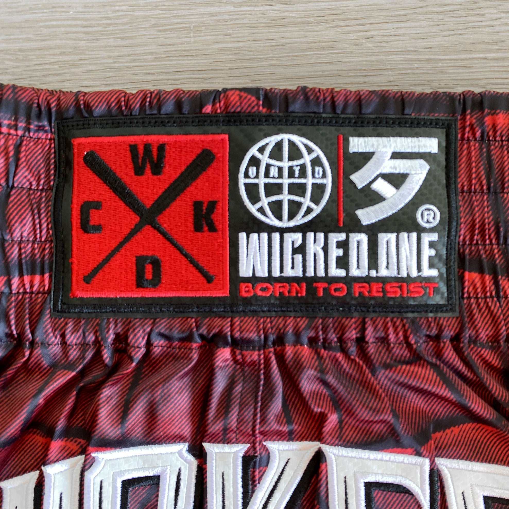 Short de Muay Thaï rouge Wicked One CAÏMAN avec coupe traditionnelle et fentes latérales pour liberté de mouvement.