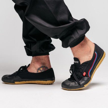 Chaussures Shaolin FUJIMAE noires portées aux pieds avec un pantalon noir