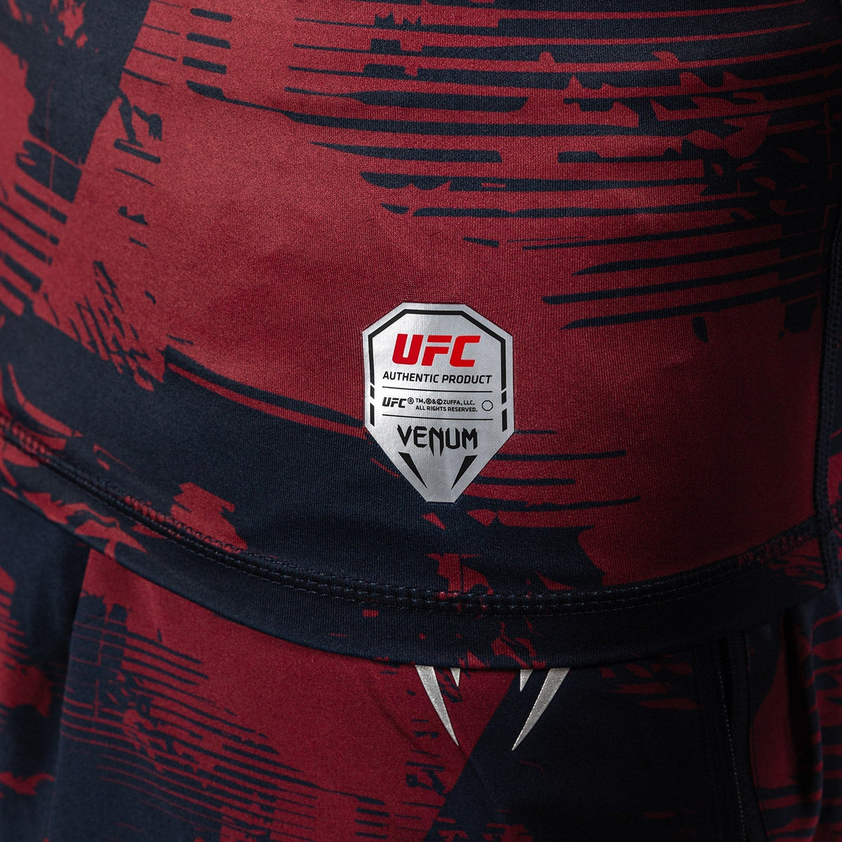 Rashguard MC Performance UFC à manches courtes, en compression bordeaux et bleu marine, motifs graphiques et logo officiel.