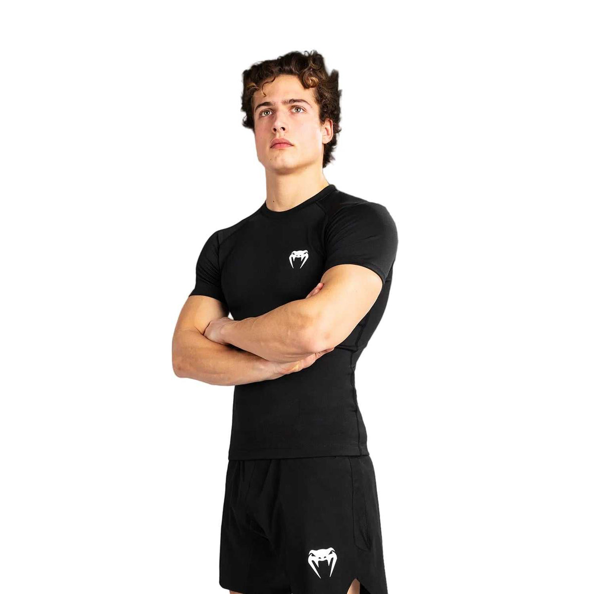 Rashguard à manches courtes noir en tissu de compression, avec logo blanc Venum et coupe près du corps.