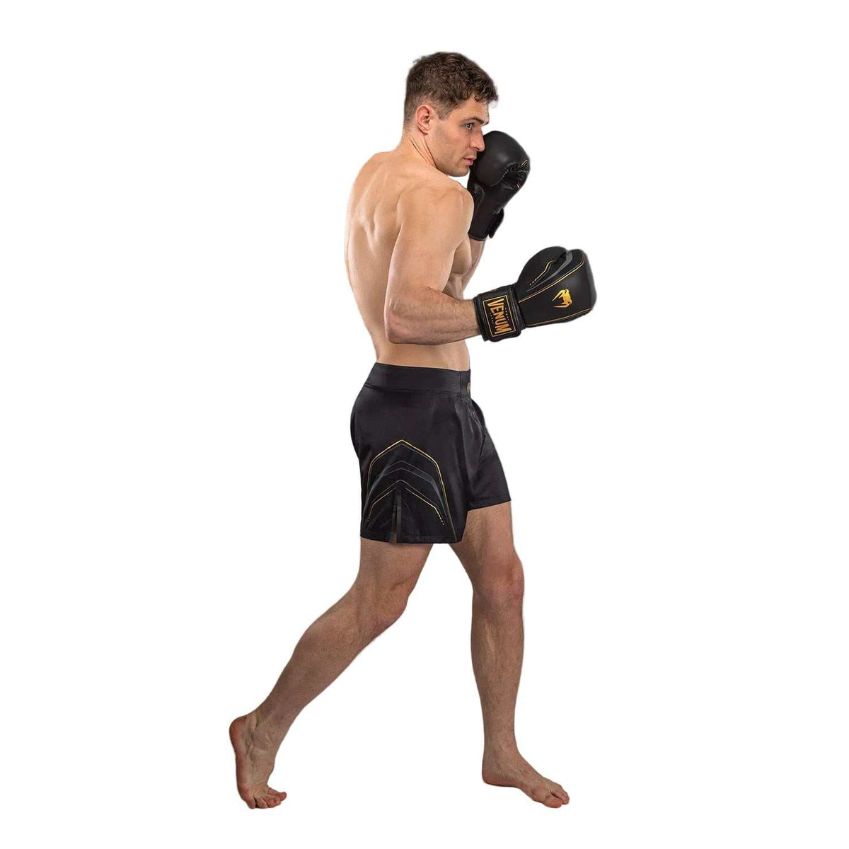 Short de combat noir en polyester, motifs géométriques dorés et fentes latérales pour une liberté de mouvement optimale.