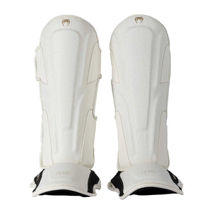 Protège-tibias Venum Impact Evo Scales ivoire en cuir Skintex pour boxe thaï, kickboxing et MMA, mousse multi-densités et maintien velcro sécurisé.